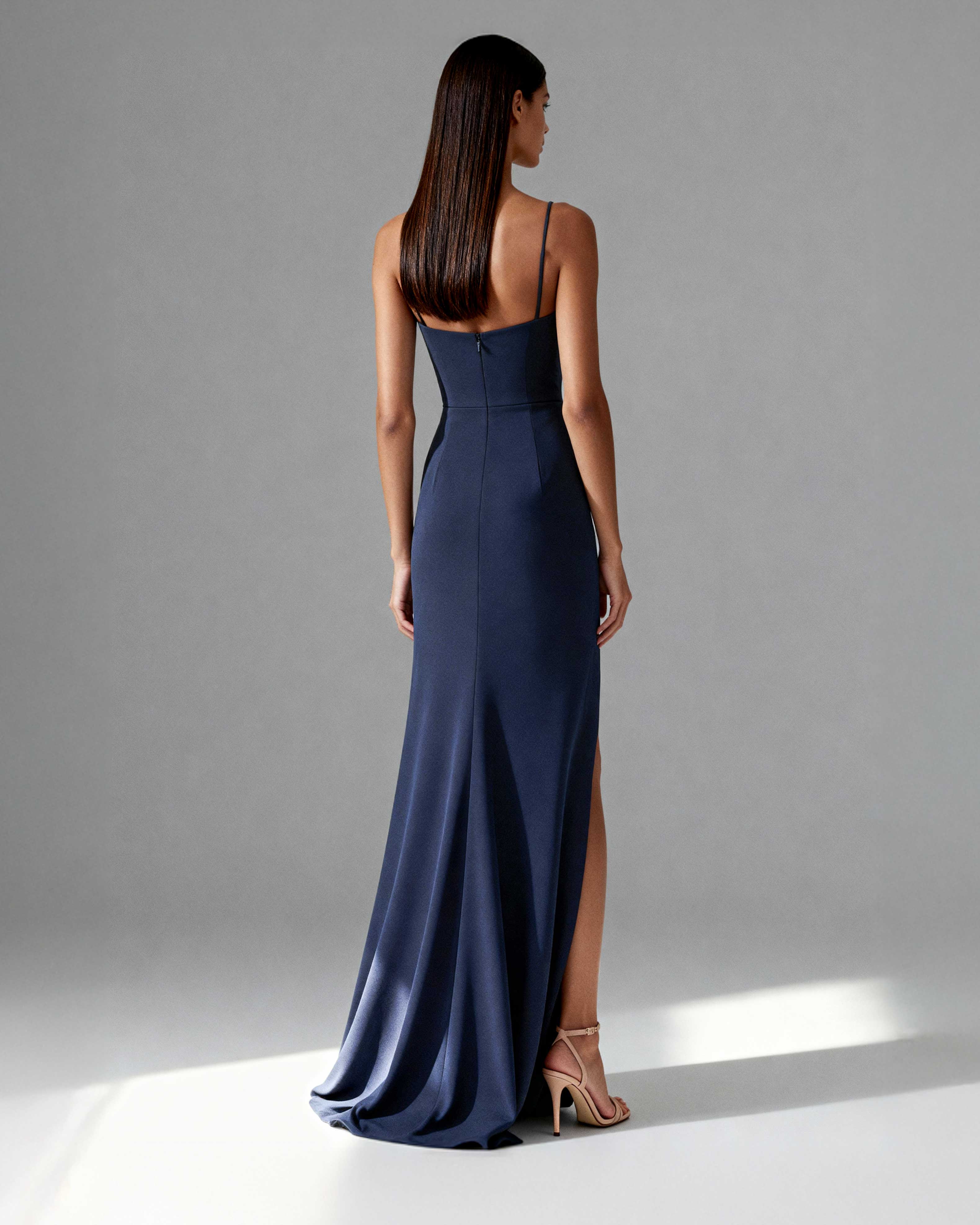 Angled back shot of floor-length gown highlighting high slit and flowing fabric