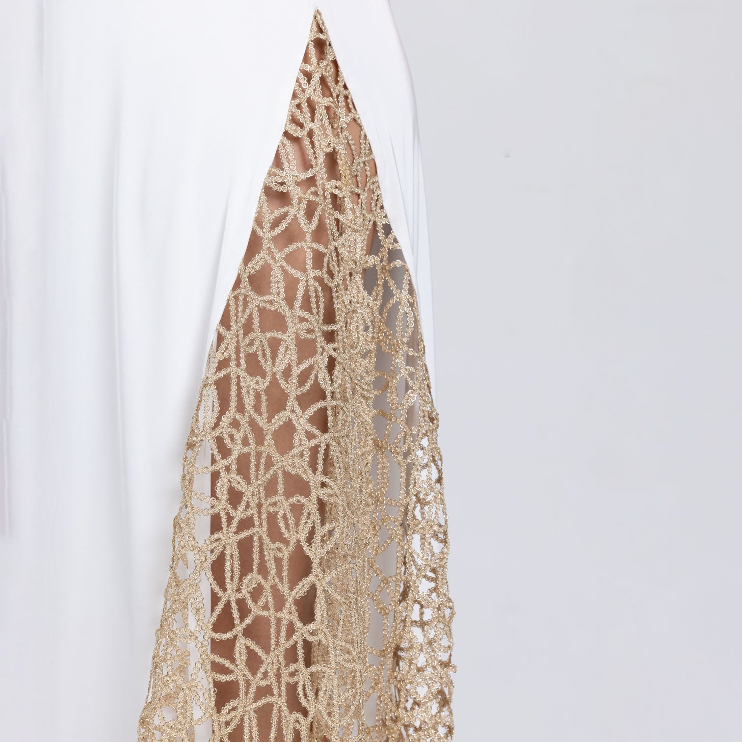Detail of gold lace panel on white satin dress – refined couture embellishment