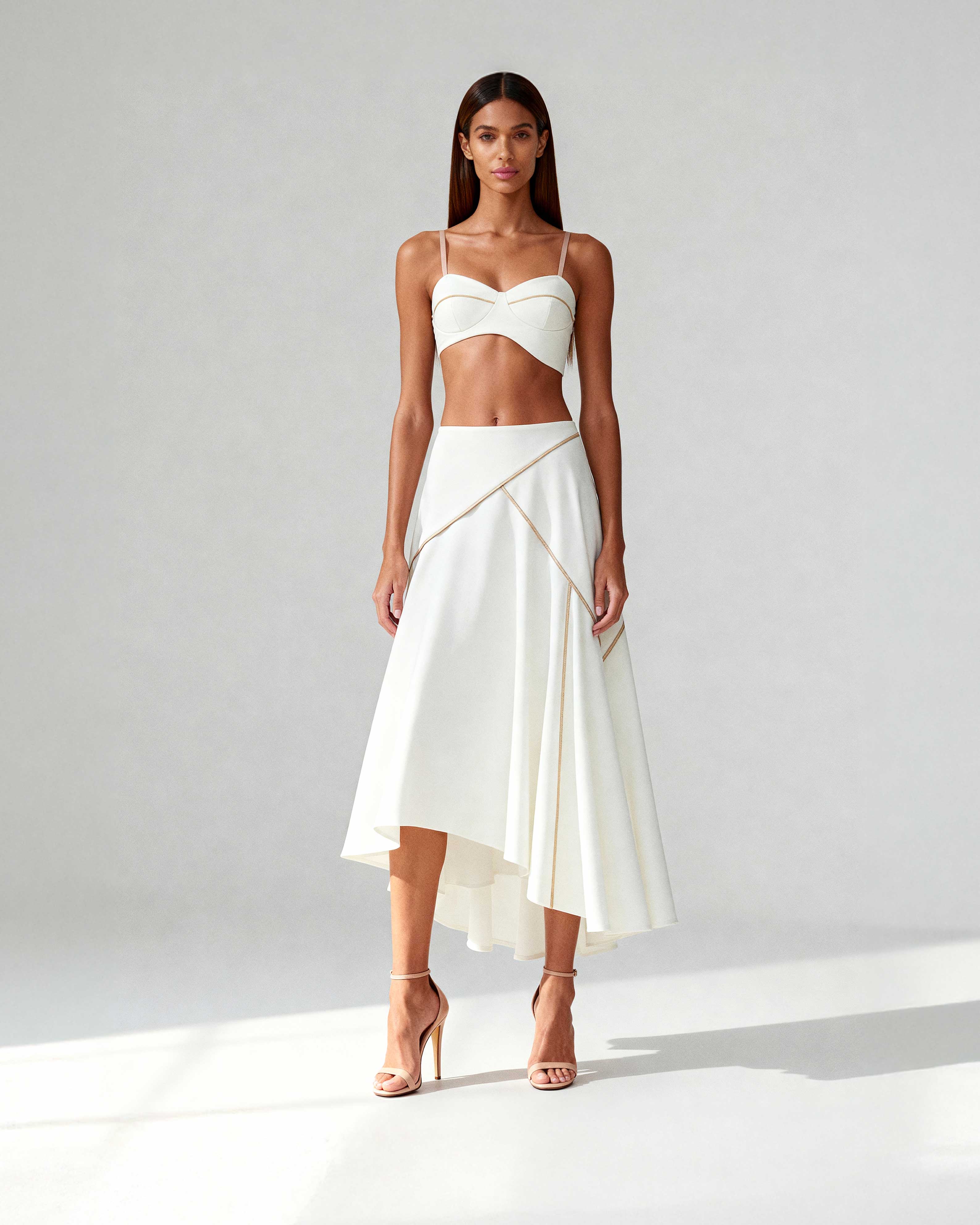 Model wearing white bustier top and flared midi skirt in coordinated crepe set, photographed full-length.