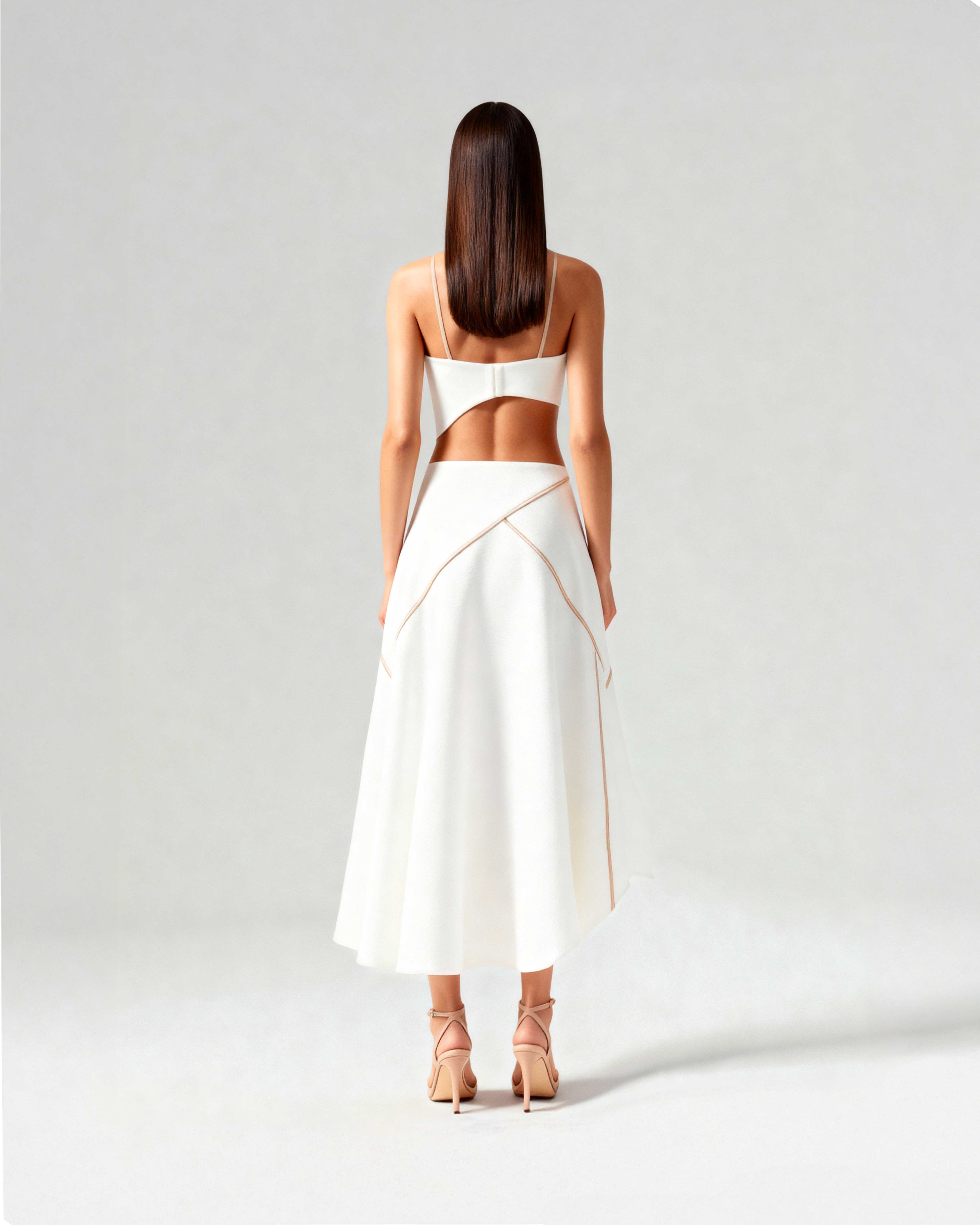 Back view of coordinated white set with strappy bustier and flared midi skirt, worn by model standing tall.