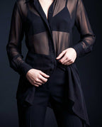Detail of the black sheer silk chiffon shirt showing the button front, long transparent sleeves and asymmetric draped hem by A|LOUD