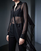 Side detail of the black sheer silk chiffon shirt showing the sheer silk chiffon drape and tailored black trousers by A|LOUD