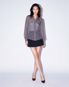 Front view of the ÉLYR sheer charcoal silk chiffon shirt styled with a black mini skirt by A|LOUD