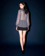 Side view of the ÉLYR sheer charcoal silk chiffon shirt styled with a structured black mini skirt by A|LOUD