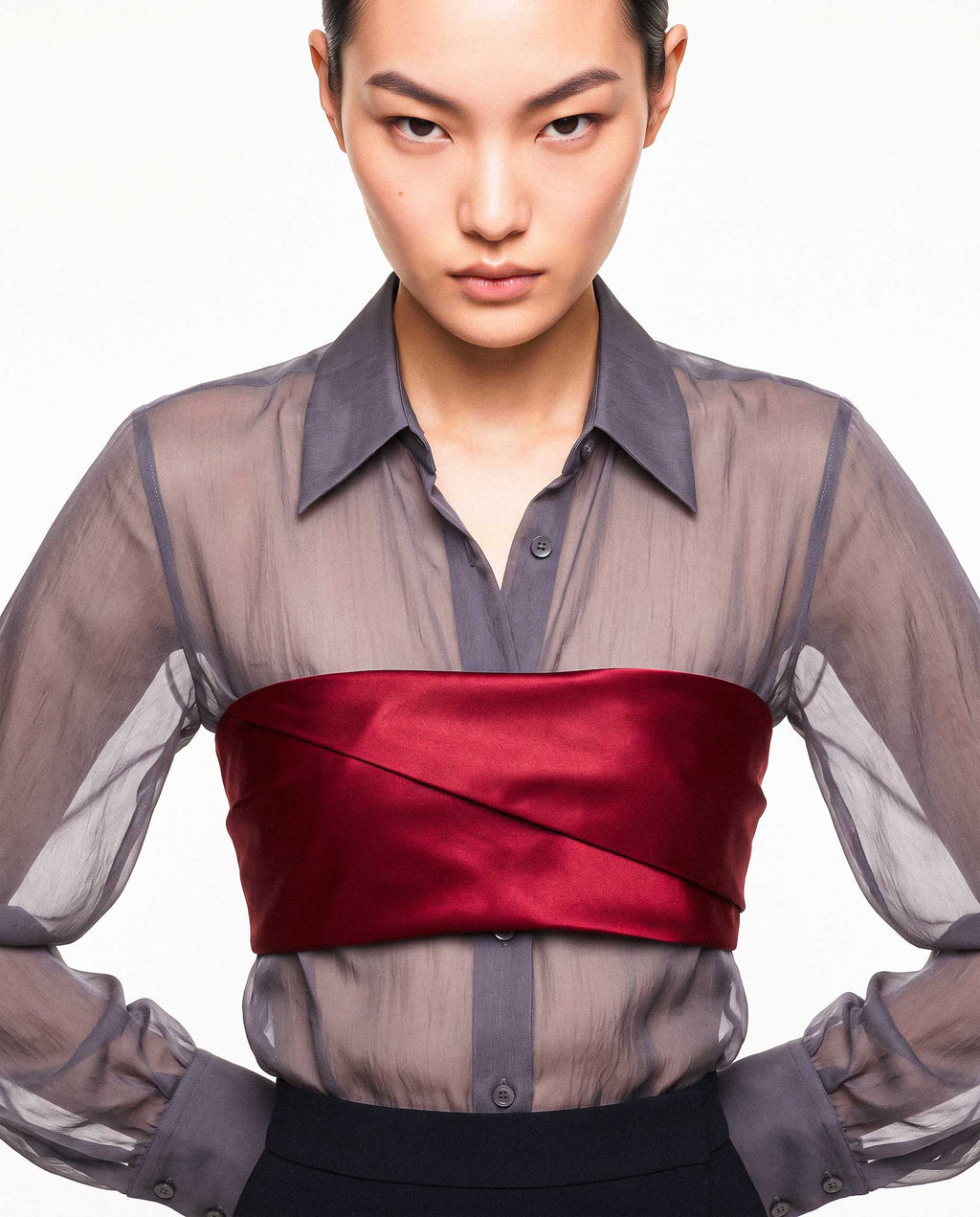 Close-up of the ÉLYR sheer charcoal silk chiffon shirt styled with a burgundy silk satin bandeau, showing the transparent texture, pointed collar and sculptural satin wrap by A|LOUD