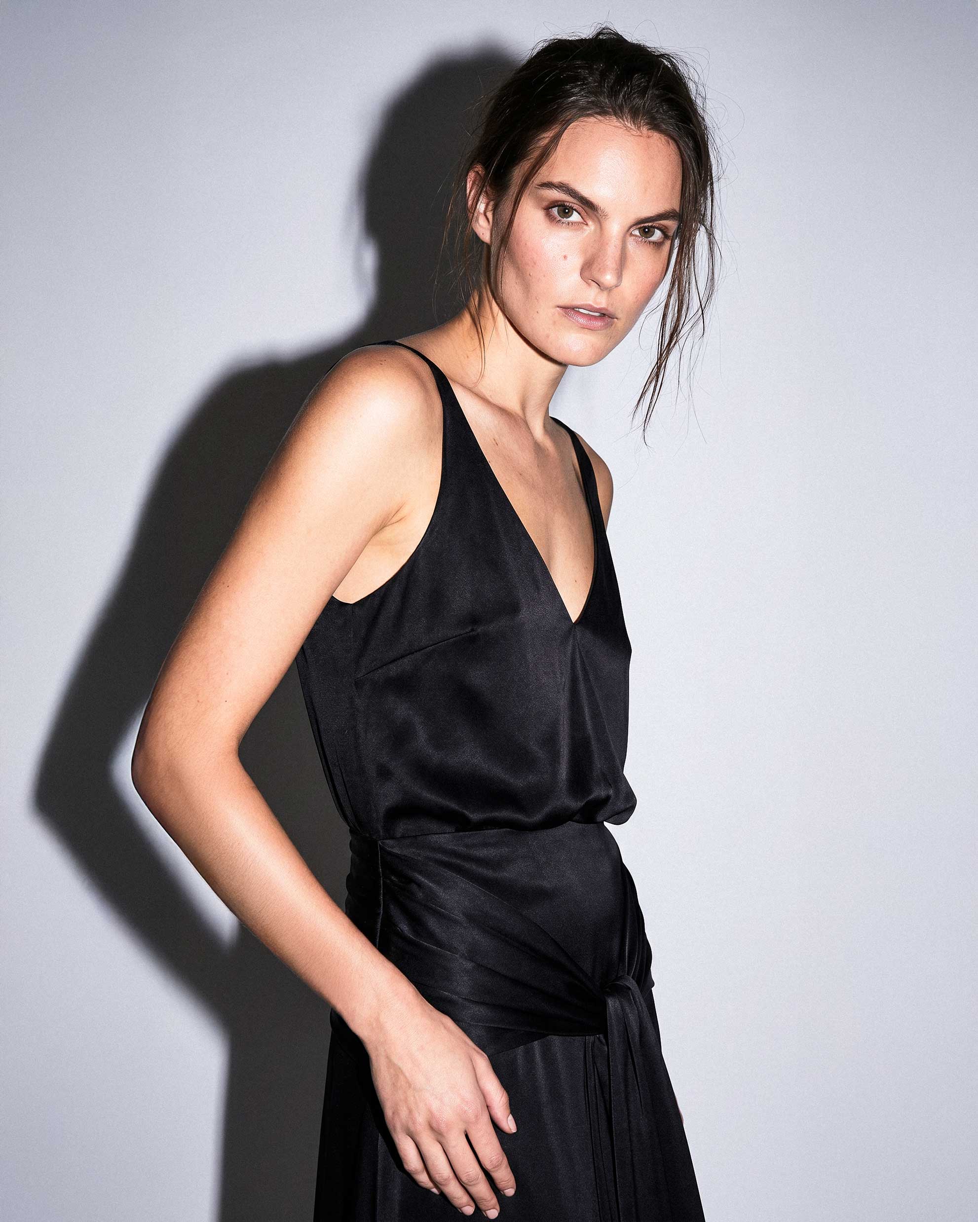 Black satin gown in motion with draped waist and elegant evening silhouette