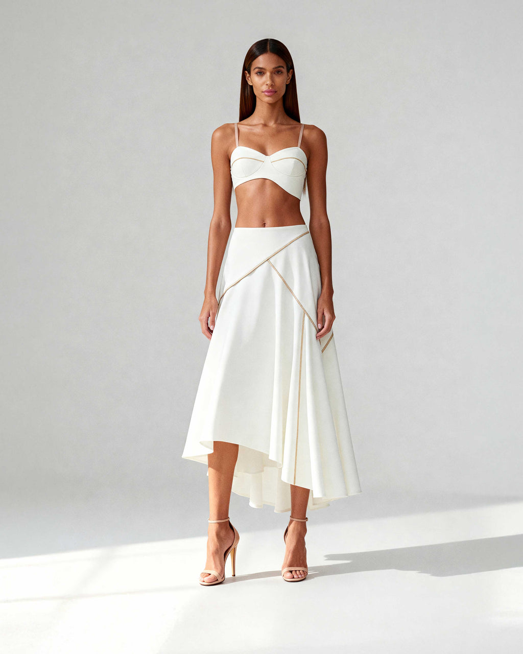 Model wearing white bustier top and flared midi skirt in coordinated crepe set, photographed full-length.