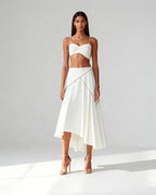 Model wearing white bustier top and flared midi skirt in coordinated crepe set, photographed full-length.