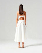 Back view of coordinated white set with strappy bustier and flared midi skirt, worn by model standing tall.