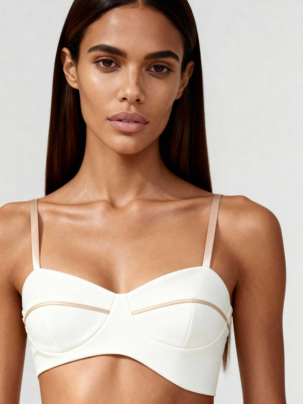 Front view of white bustier top with sculpted lines and tonal piping, worn by model with straight hair.