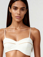 Front view of white bustier top with sculpted lines and tonal piping, worn by model with straight hair.