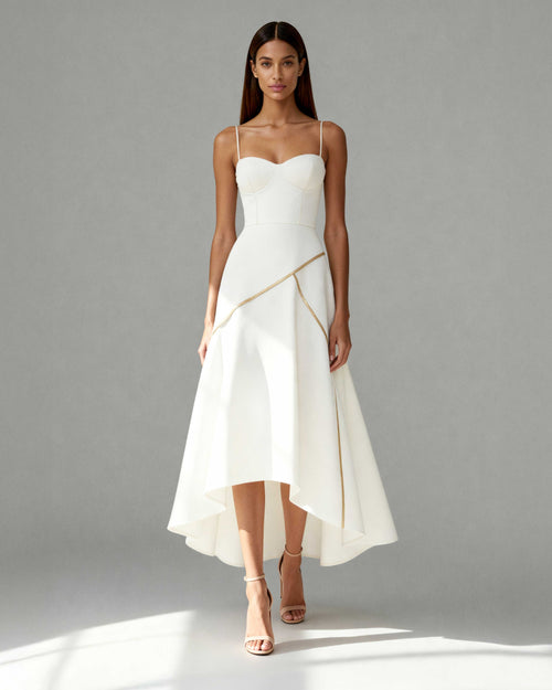 Model wearing Nayla white midi dress with gold piping, sweetheart neckline and asymmetrical hem
