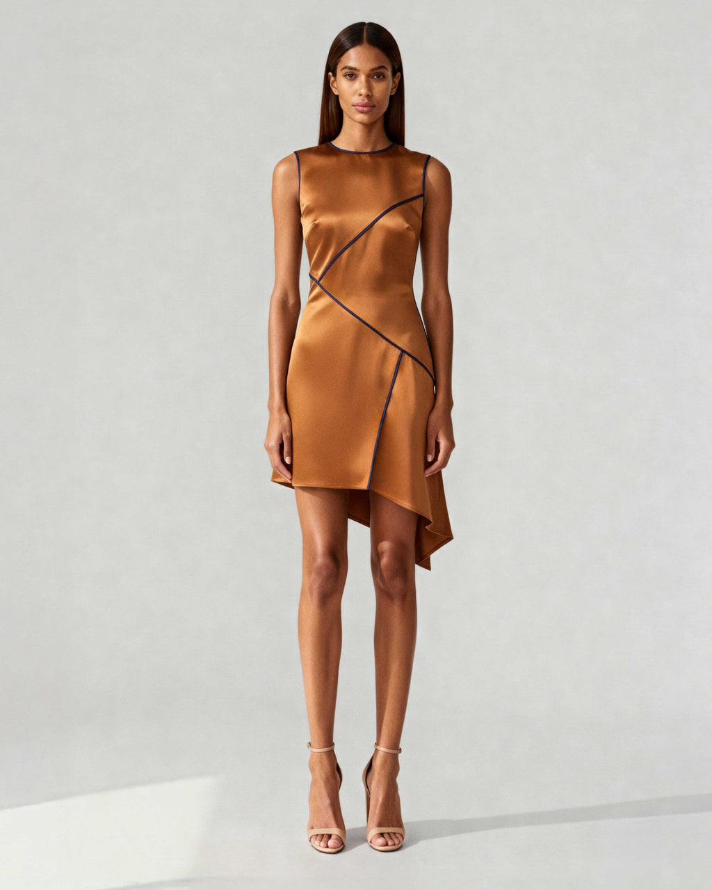 Model wearing copper satin mini dress with navy piping and asymmetric hem – front view