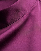 Close up of plum silk satin showing its sheen, fine texture and stitched seam.
