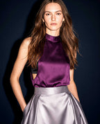 Front view of the plum silk satin top with a high neckline, styled with a silver grey pleated skirt by A|LOUD.