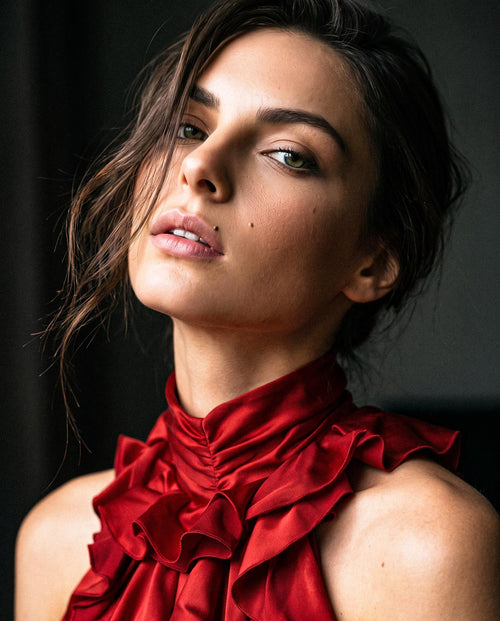 Editorial portrait showing the high neckline and sculptural silk satin ruffles of the red mini dress by A|LOUD.