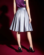 Back view of the silver grey silk satin skirt showing the waistband and deep pleats against a burgundy background.