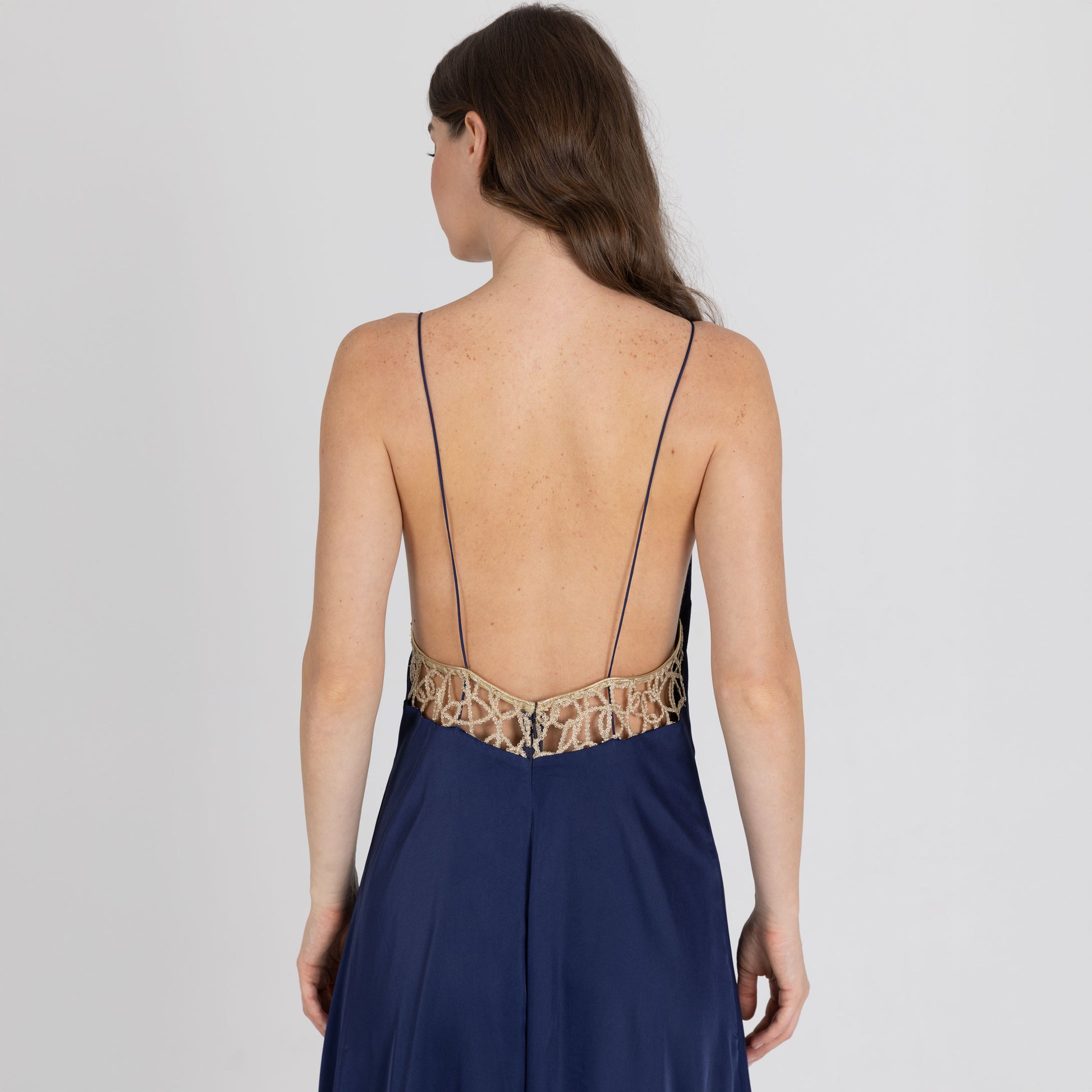 Close-up of golden lace insert on backless navy satin gown – handcrafted detailing