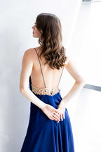Back view of the Sireya gown in blue satin, featuring a sheer embroidered panel and thin straps, worn by a model in graceful pose.