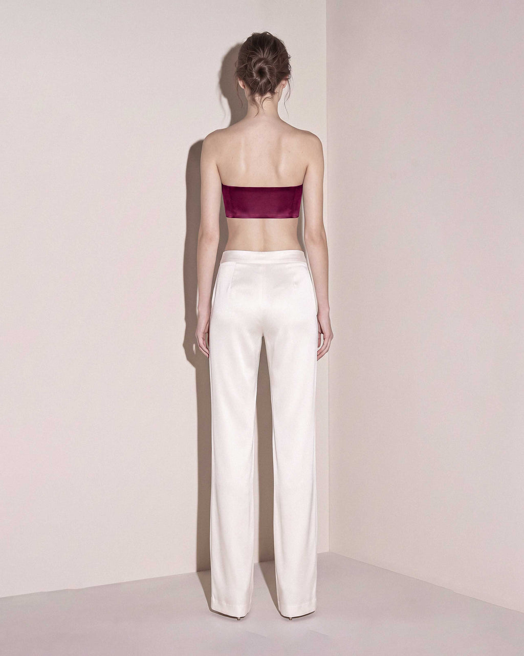 Back view of the burgundy silk satin bandeau top styled with ivory wide leg trousers