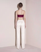 Back view of the burgundy silk satin bandeau top styled with ivory wide leg trousers