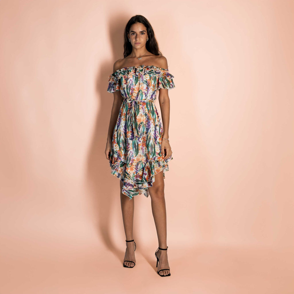 The midi dress with a feminine and sophisticated line features an elegant draped neckline and a belt at the waist that defines the silhouette. The asymmetrical ruffled skirt adds a touch of movement and grace. She completes the look with high-heeled sandals for an elegant summer evening or with ballet flats for a more casual and fresh touch.