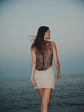 Model wearing Eline Mini Dress – sheer embroidered bodice and yellow tulle skirt at sunset