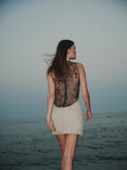 Model wearing Eline Mini Dress – sheer embroidered bodice and yellow tulle skirt at sunset