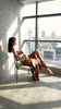 A woman seated in soft light, wearing a satin dress from the A|LOUD Ready-to-Wear collection. Stillness meets presence.